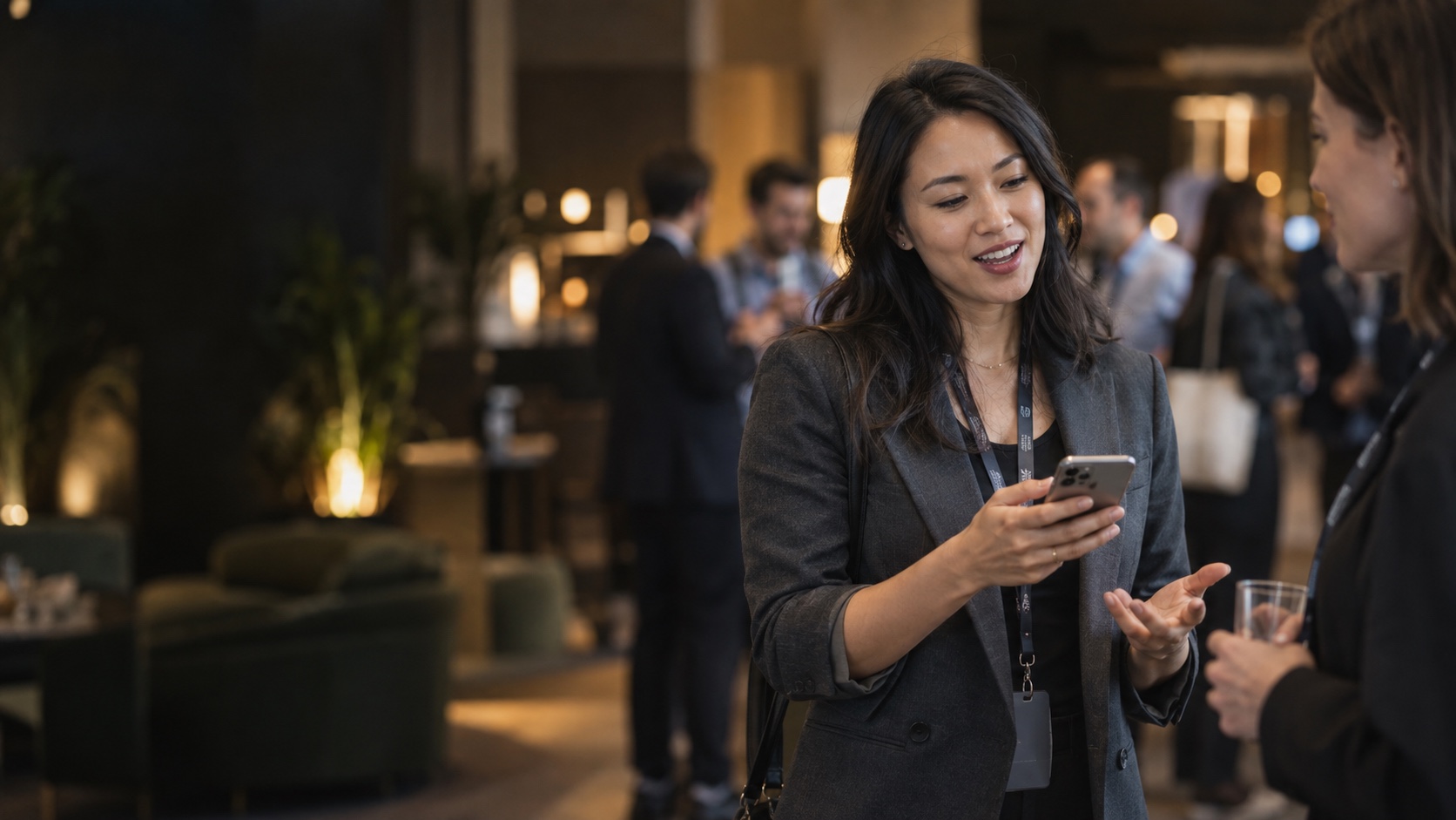 Two people talking at a conference, one checking her phone between sessions.